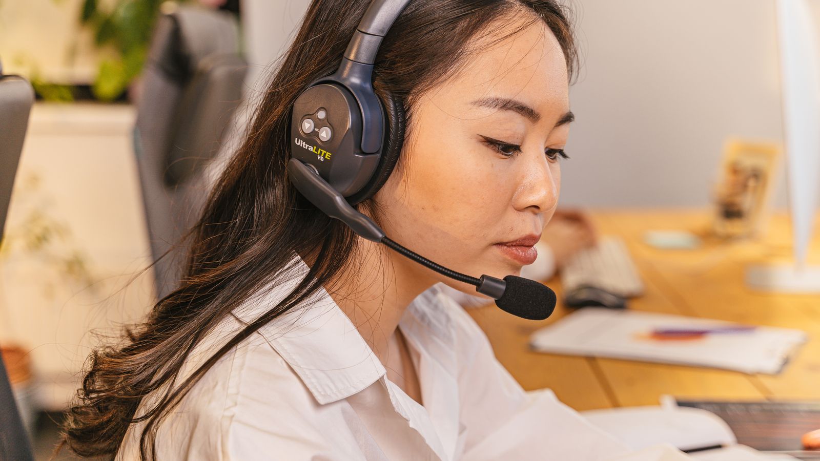 Female customer support representative wearing a headset at a computer