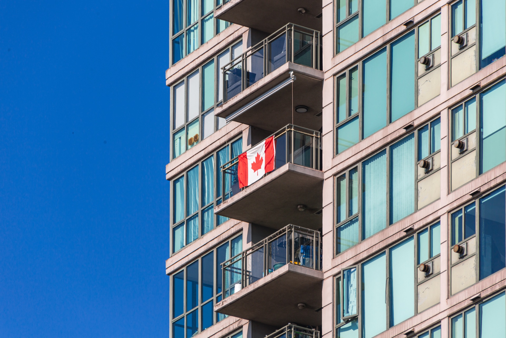 Canadian flag displayed on the balcony of a modern apartment building